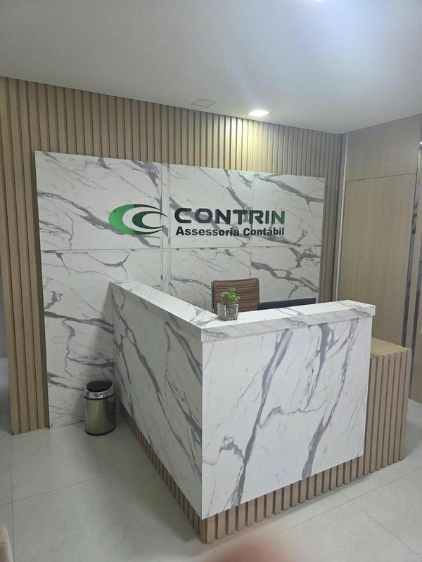 Recepção do escritório Contrin, com o logotipo na parede de mármore e o balcão de atendimento